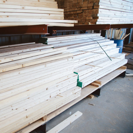 Lumber & Building MaterialsStacks of neatly arranged light-colored wooden planks in a warehouse setting, creating a sense of order and readiness for construction projects.